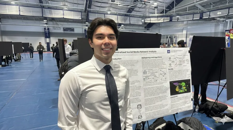 Ruslan Zabarov standing beside his research poster